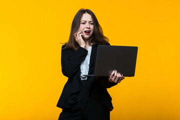 A young woman is talking on the phone and looking at the laptop screen.Studio business shooting.