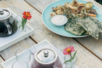Various fried vegetables include spinach leaves, broccoli, and carrot served with mayonaise sauce on a green plate