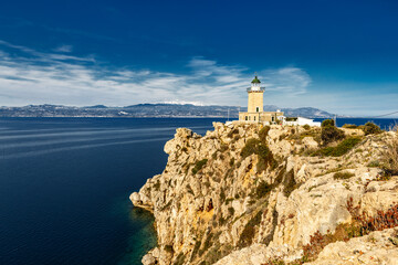 Lighthouse at cape Ireon in Greece, Europe, on clear sunny day. Wide-angle epic scene of rocky cape with stone lighthose on top.