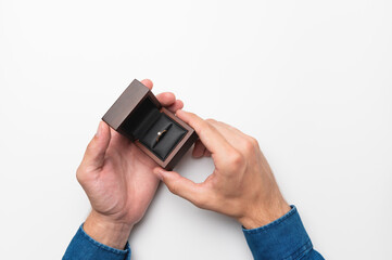 a man's hand holds a diamond engagement ring in a wooden elegant box, making a marriage proposal