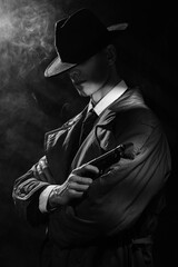 A dark silhouette of a man in a raincoat and hat with a gun in his hands in the style of crime noir. A dramatic noir portrait in the style of detectives of the 1950s.