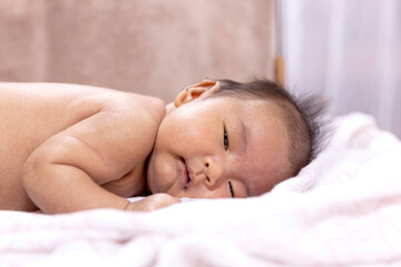 Obraz na płótnie Canvas Cute asian newborn baby lying on white fur towel,portrait of little child boy,five week old.