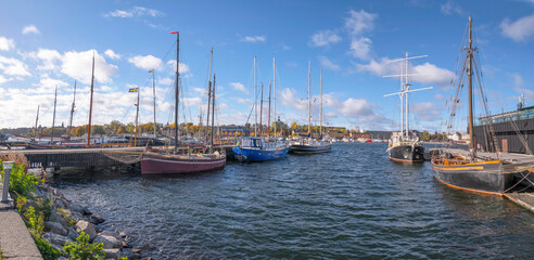 Old sail ships at a pier in the bay Ladugårdsviken and skyline over the island Skeppsholmen a colorful sunny autumn day in Stockholm