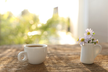 Coffee cup and pot and paris daisy flower on wooden table outdoor