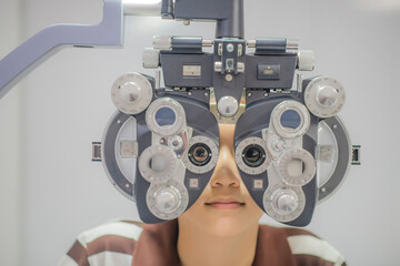 Nearsighted boy tests eyesight with optical projector in optics lab.
