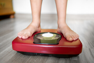 Fototapeta premium Closeup view of scales on a floor and kids feet at room