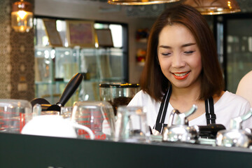 Beautiful Asian woman making coffee for customers. Coffee shop concept. Small Business, SME, Entrepreneur, Professional Barista