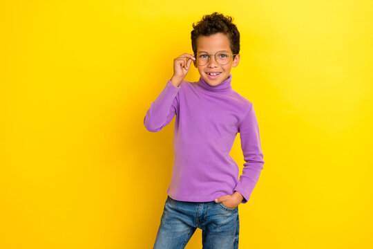 Photo of positive schoolchild hand touch glasses beaming smile isolated on yellow color background