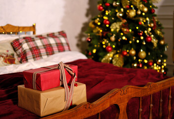 Christmas gifts tied with a ribbon lie on the bed against the backdrop of the Christmas tree
