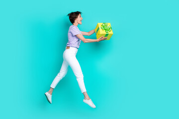 Fototapeta na wymiar Full length photo of sweet shiny lady wear violet t-shirt giving present empty space jumping high isolated turquoise color background