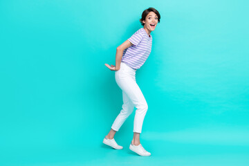 Photo of impressed shocked girl dressed purple t-shirt holding back amrs empty space isolated teal color background