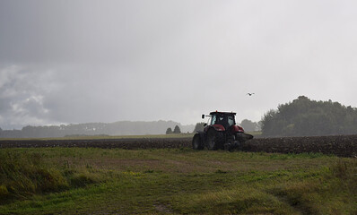 Fototapeta premium tractor with plow on field in bad weather