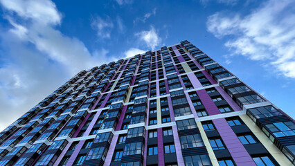 The facade of the building in purple,geometric patterns from windows and balconies, the colored wall of a modern multi-storey residential building, the abstract texture of the facade of the house