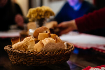 Bites of fresh white bread in a basket on a table in a restaurant. People on background