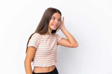 Little caucasian girl isolated on white background listening to something by putting hand on the ear