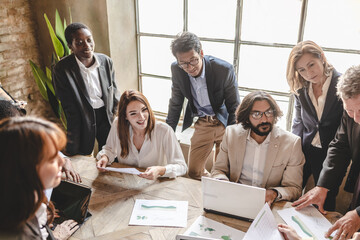 Group of multiethnic businesspeople operating in a renewable power analyze data about electric energy.