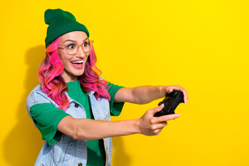 Photo of funny impressed eccentric girl pink hairdo dressed denim waistcoat hold play station joystick isolated on yellow color background