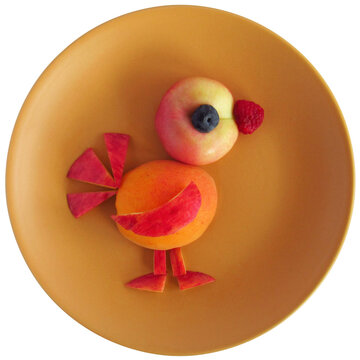 A funny bird made of fruit on a plate.