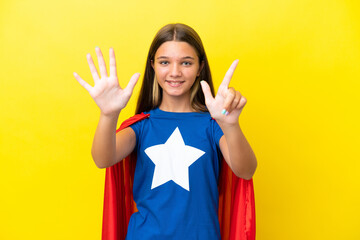 Little caucasian superhero girl isolated on yellow background counting seven with fingers