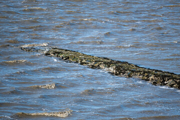 old stone wall juts into the sea