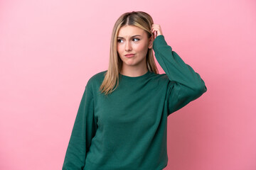 Young caucasian woman isolated on pink background having doubts