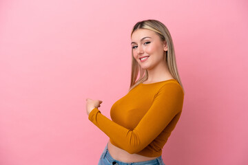 Young caucasian woman isolated on pink background pointing back