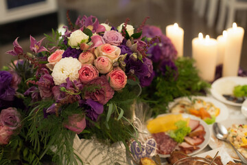 Festive served table for the bride and groom, decorated with flowers in vases, at a banquet, in a restaurant.