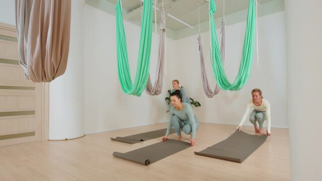 Group of young women getting ready for an aerial yoga class in hammocks