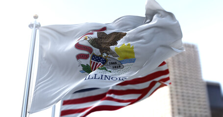 The Illinois state flag flapping in the wind with the American national flag blurred in the...
