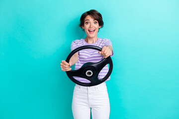 Photo of impressed nice cute girl with bob hairdo striped t-shirt hold steering wheel excited staring isolated on teal color background