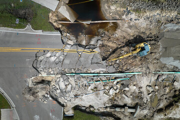 Aerial view of reconstruction of damaged road bridge destroyed by river after flood water washed away asphalt. Rebuilding of ruined transportation infrastructure