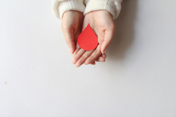 hand blood drop shape made from paper on white background, copy space, top view. blood donation concept, world blood donor day