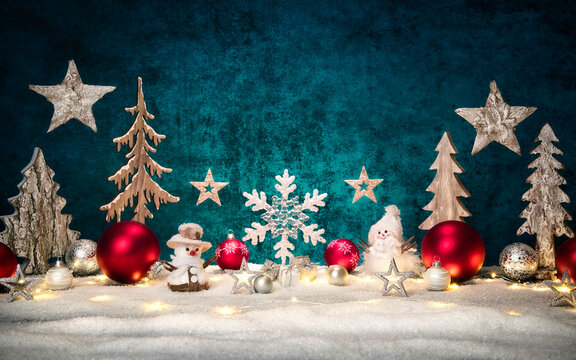 Christmas ornamental arrangement with stylish teal copy space, red and silver baubles, lights, snow, wooden decoration and snowman figures