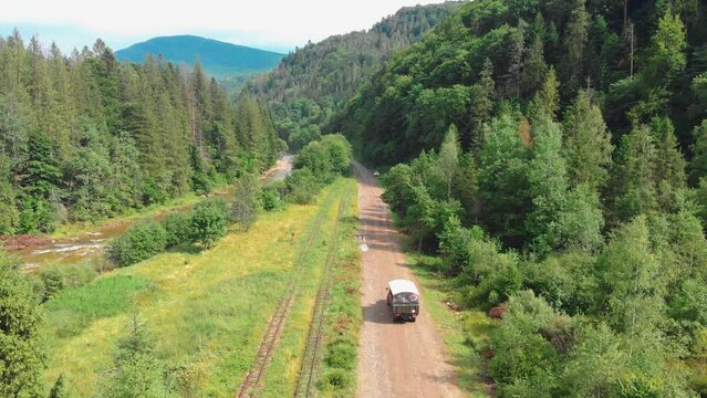 The truck is traveling along a mountain road on tourist route. A tourist trip through Ukrainian Carpathians in the summer. Big green tourist car Zil. Rest in nature among the river and green forests.