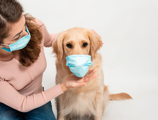 A girl helps the dog to wear a protective mask because with the virus for protection themself isolated