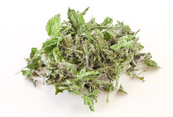 Handful of dry nettle herbs isolated on white background. Aromatic traditional condiment