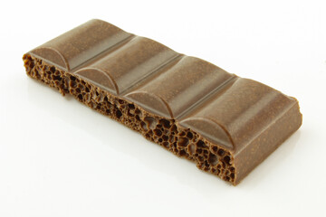 Piece of bubbly milk chocolate isolated on white background