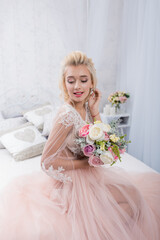 Beauty fashion bride in interior studio with bouquet of flowers in her hands. Beautiful Bride portrait wedding makeup and hairstyle. Fashion bride model in luxury wedding dress.