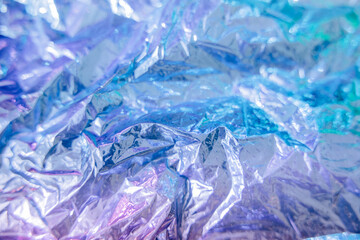 Iridescent foil texture background. Holographic wrinkled surface. Vibrant gradient template for design.