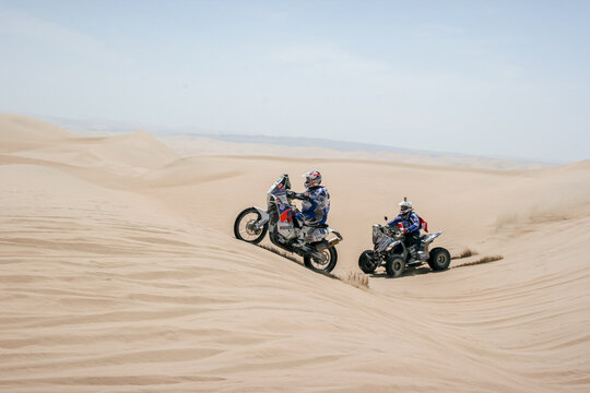Ica, Peru; January 2013: Motorcyclists and quad crossing the Peruvian desert, in the middle of the sand dunes. 