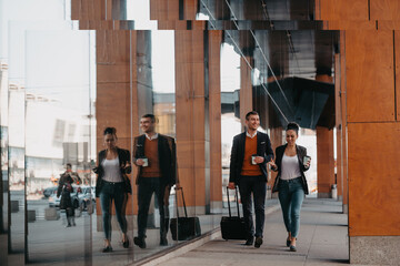 Business man and business woman talking and holding luggage traveling on a business trip, carrying fresh coffee in their hands.Business concept