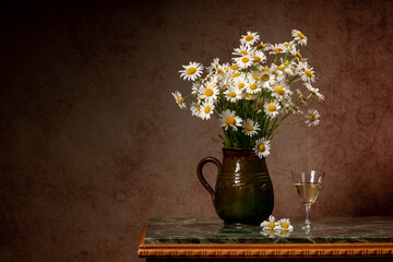 A large bouquet of white daisies in a brown clay jug on a marble green table. Near the glass of white wine and the inscription love. Fun summer still life. Thoughtfulness