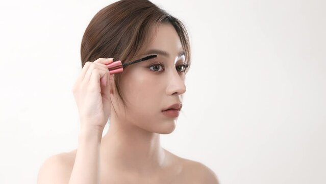 Beauty concept of 4k Resolution. Asian woman brushing eyelashes on a white background.