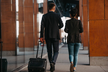 Business man and business woman talking and holding luggage traveling on a business trip, carrying fresh coffee in their hands.Business concept