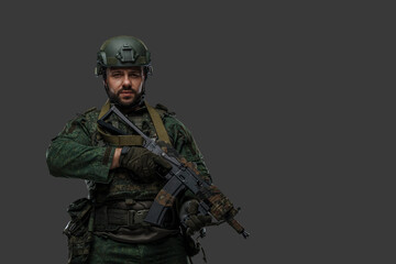 Studio shot of modern russian soldier dressed in camouflage uniform against grey background.