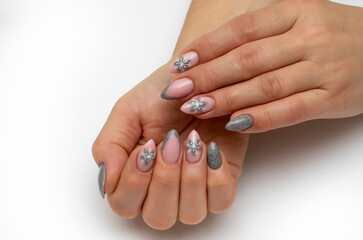 New Year's manicure with snowflakes. Silver manicure on long sharp nails dissolves on a white background.	