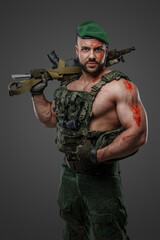 Portrait of troop soldier with muscular build holding rifle looking at camera.