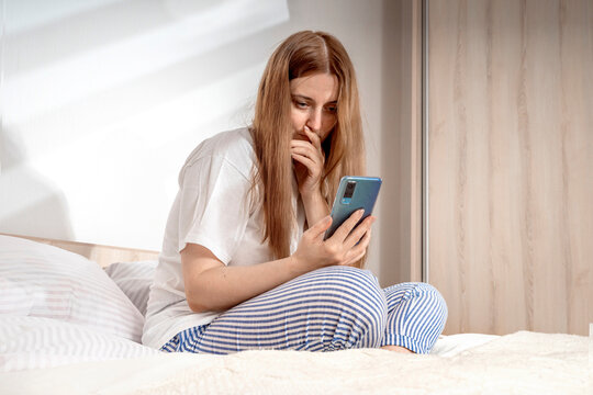 Woman with smartphone in bed at home or hotel in the morning. Lady relaxing in a nightgown. Girl wearing nightie on clean white bedding, cozy blanket