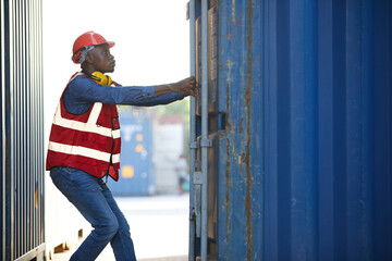 Fototapeta na wymiar African factory worker or foreman opening the container door in warehouse storage