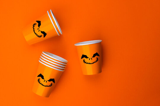 Halloween party background with Paper cup with Jack lantern face decoration. Disposable cup made of recycled paper orange colors. Pattern for outumn october holiday all saints day celebration